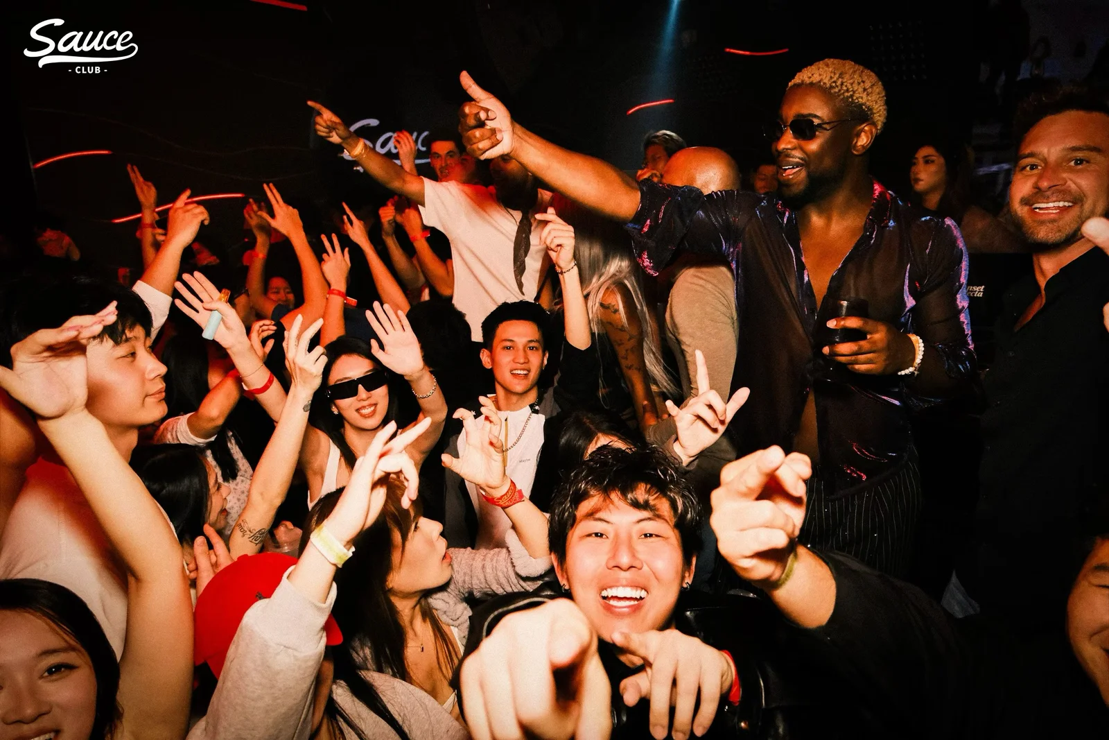 Travelers dancing and raising their hands together at an evening party