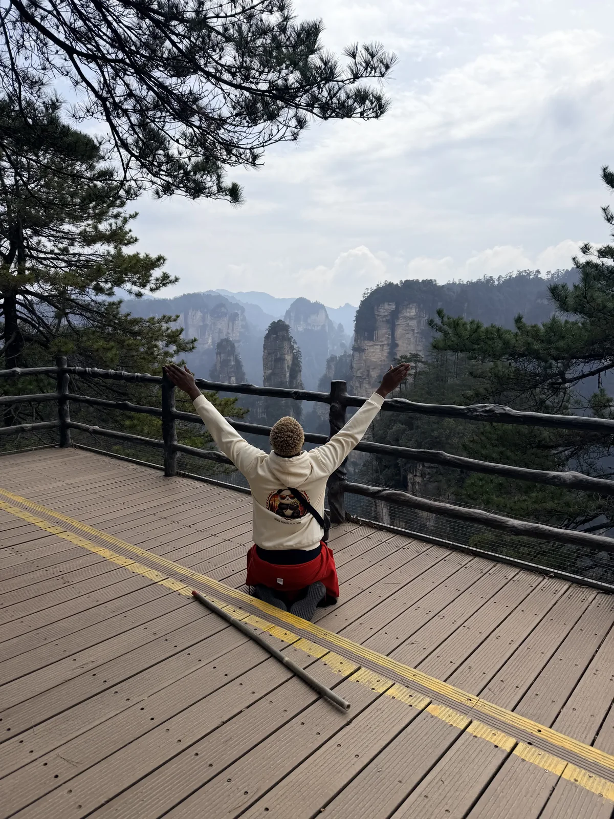 A traveler holding her arms open on a mountain viewing platform