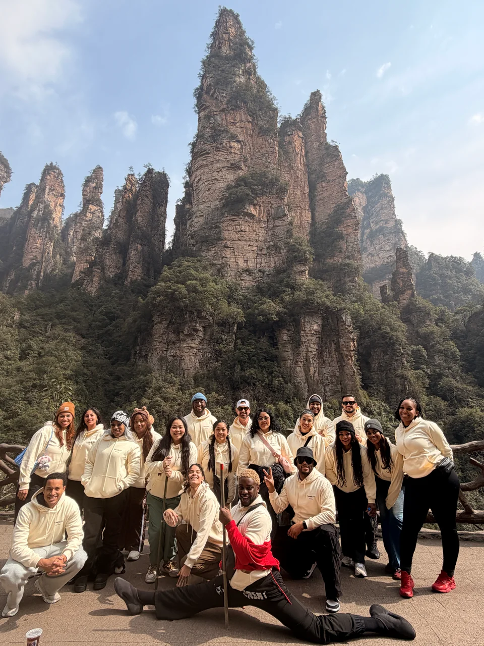 The travel group posing beneath tall rocky mountain peaks on a sunny day