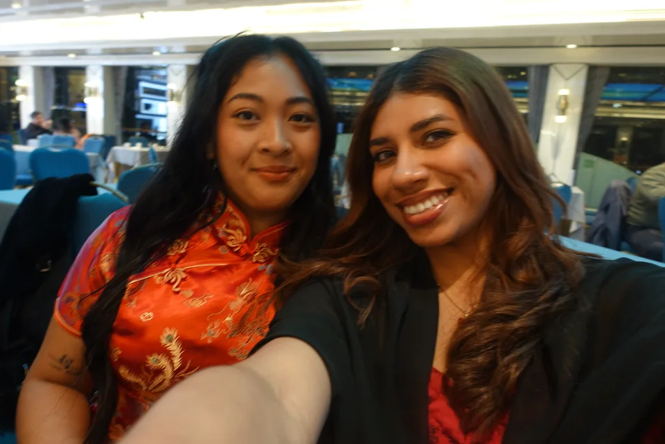 Two friends smiling together for a selfie inside a bright dining room