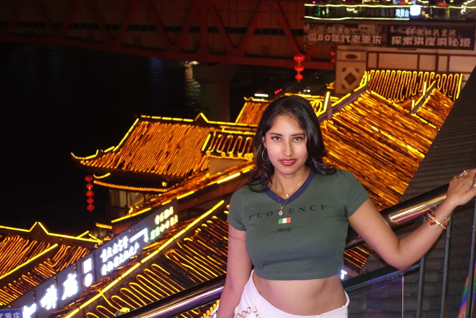 A traveler standing at a railing above traditional rooftops outlined in golden lights