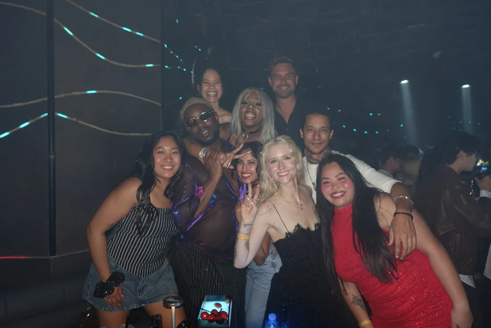 Friends gathered for a group photo under blue lights during an evening out