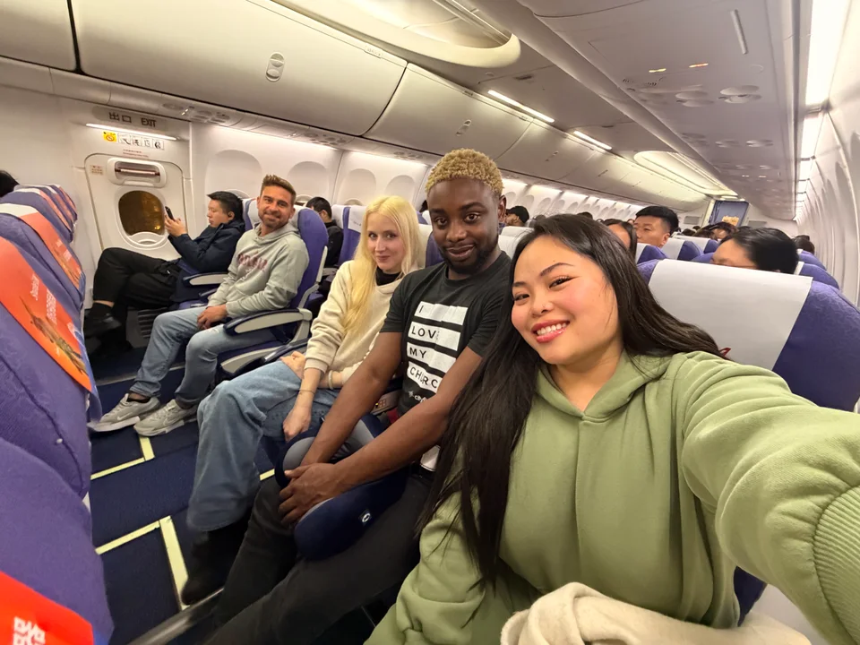 Friends smiling from neighboring rows of seats inside a train carriage