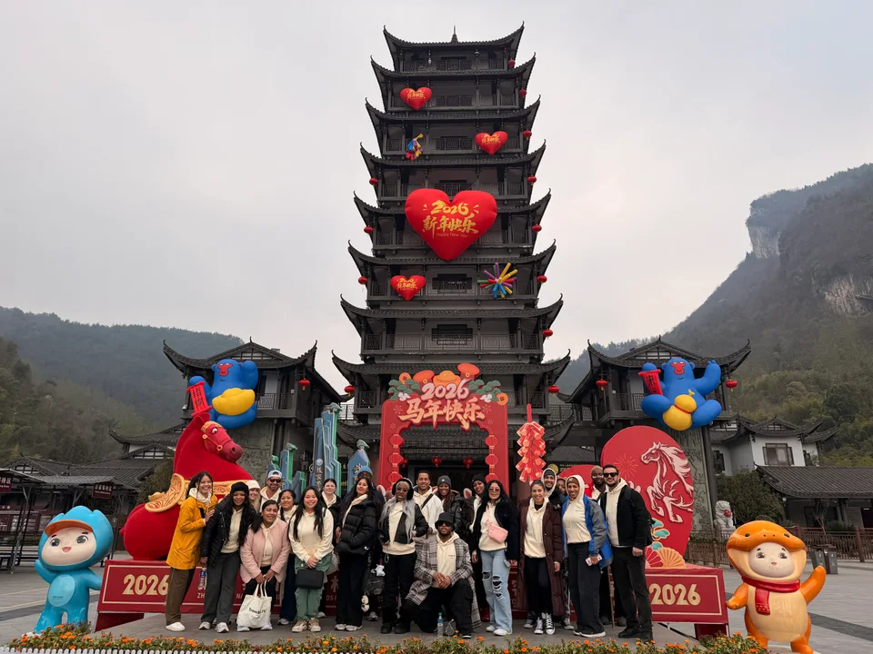 The group posing beneath a tall pagoda decorated with red lanterns and colorful figures