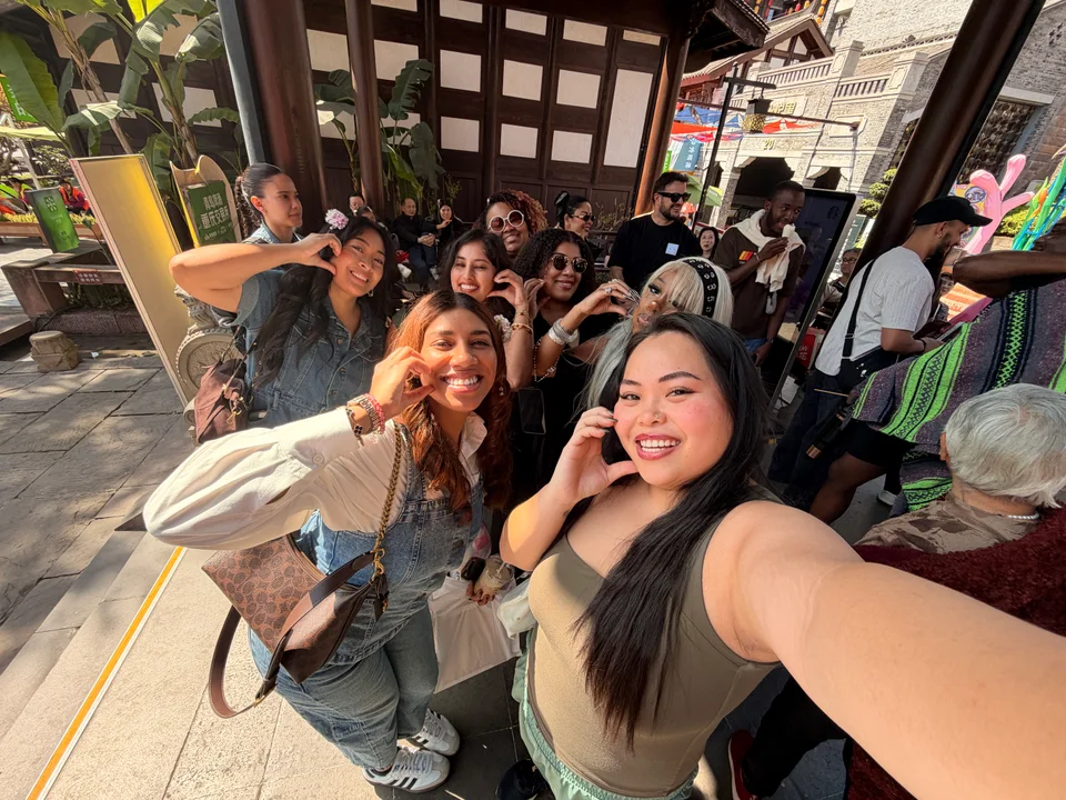 Friends smiling for a group selfie under a timber-covered outdoor terrace