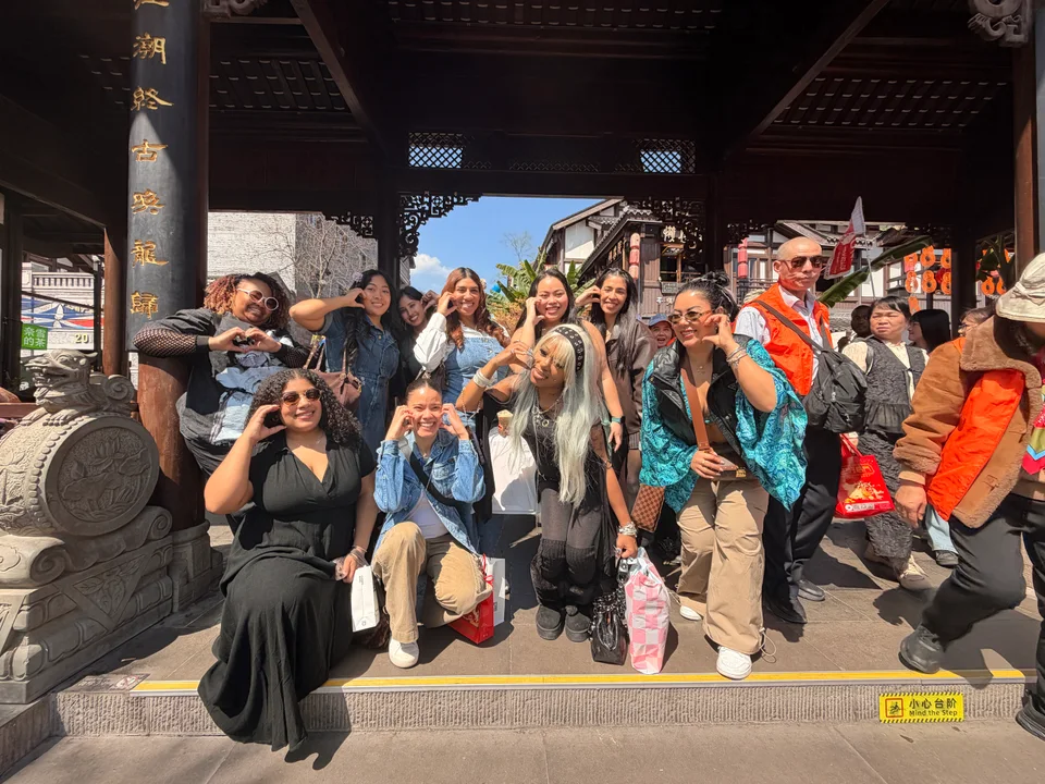 The group posing on stone steps beneath a carved wooden gateway