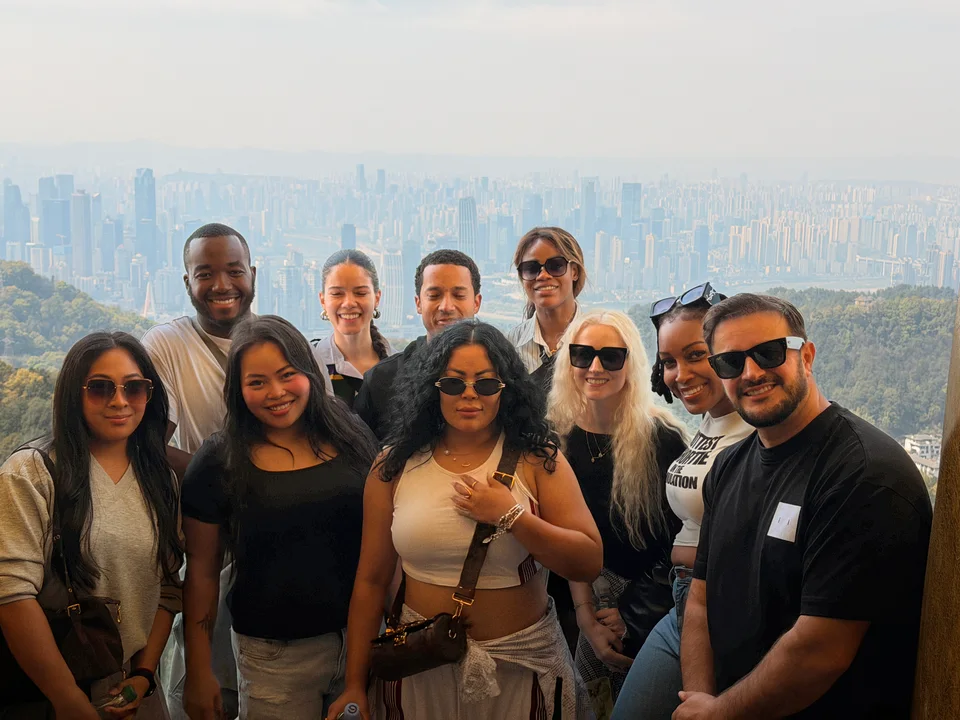 Friends gathered at a hilltop viewpoint with a hazy city skyline behind them